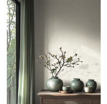 Vases ronds en céramique avec glaçure craquelée et branches sur une console en bois dans une pièce au design moderne près d'une fenêtre.