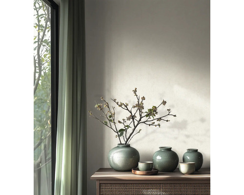 Vases ronds en céramique avec glaçure craquelée et branches sur une console en bois dans une pièce au design moderne près d'une fenêtre.