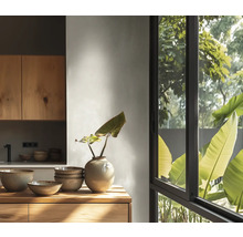 Cuisine lumineuse avec meubles en bois, bols en céramique et vase sur un plan de travail en bois devant une grande fenêtre donnant sur des plantes.