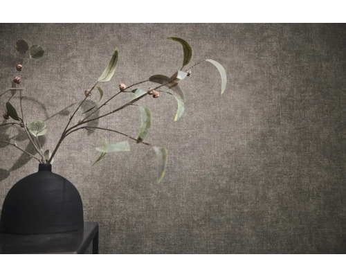 Papier peint texturé aspect lin avec un vase noir et des branches au premier plan.