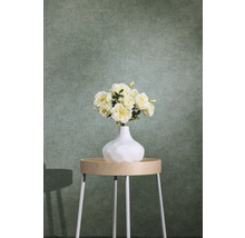 Papier peint intissé structuré vert avec aspect textile derrière une table d'appoint avec un vase à fleurs.
