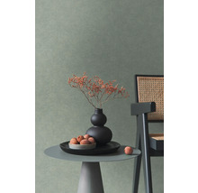 Mur avec papier peint texturé dans une pièce moderne avec table d'appoint, vase et chaise en cannage.