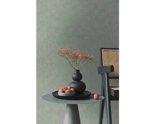 Mur avec papier peint texturé dans une pièce moderne avec table d'appoint, vase et chaise en cannage.