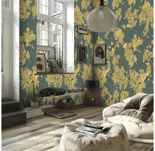 Salon moderne avec papier peint intissé à motifs de fleurs jaunes sur fond sombre, parquet et pouf clair.