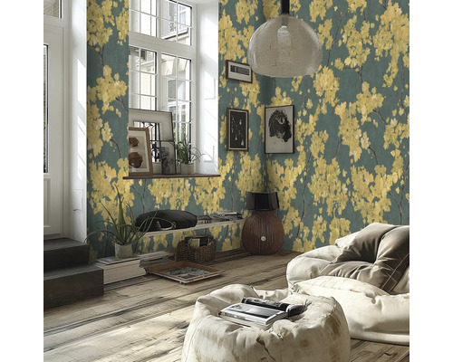 Salon moderne avec papier peint intissé à motifs de fleurs jaunes sur fond sombre, parquet et pouf clair.