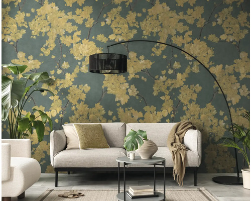 Salon avec papier peint intissé au motif floral, fleurs jaunes sur fond vert foncé, canapé gris clair et lampadaire à arc noir.