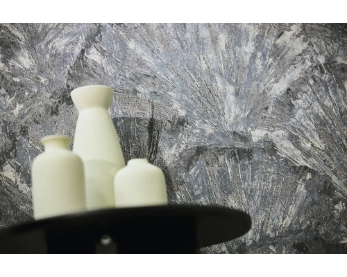 Papier peint texturé avec motif abstrait gris et blanc derrière trois vases blancs.