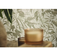 Papier peint intissé avec motif botanique de feuilles et de branches dans une pièce avec des bougies et des plantes.