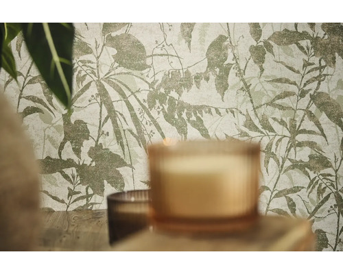Papier peint intissé avec motif botanique de feuilles et de branches dans une pièce avec des bougies et des plantes.