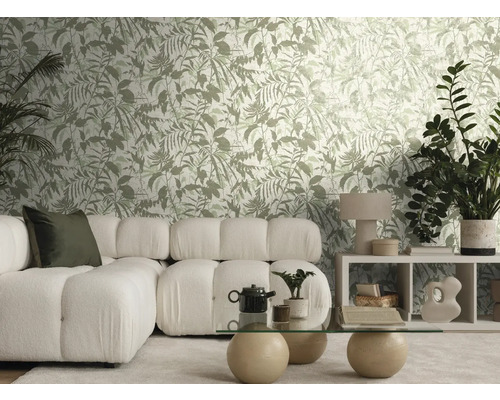 Salon lumineux avec papier peint à motif botanique, canapé modulaire blanc, table en verre avec boules de pierre et plantes d'intérieur.