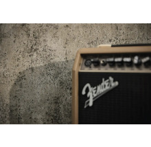 Logo Fender sur un amplificateur de guitare devant un mur à l aspect béton texturé.