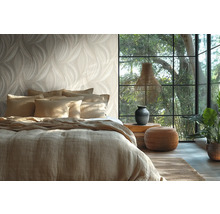 Chambre à coucher lumineuse avec papier peint à motif de feuilles, lit avec housse en lin, grande fenêtre et éléments de décoration naturels.