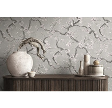 Papier peint au motif floral de branches fleuries derrière un buffet en bois avec des vases décoratifs.