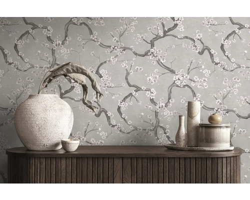 Papier peint au motif floral de branches fleuries derrière un buffet en bois avec des vases décoratifs.