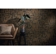 Décoration murale avec papier peint géométrique marron et noir, fauteuil en cuir marron avec coussin et plante verte sur un guéridon.
