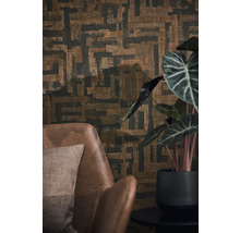 Papier peint intissé avec motif géométrique abstrait et aspect tissé derrière un fauteuil en cuir marron et une plante d'intérieur.
