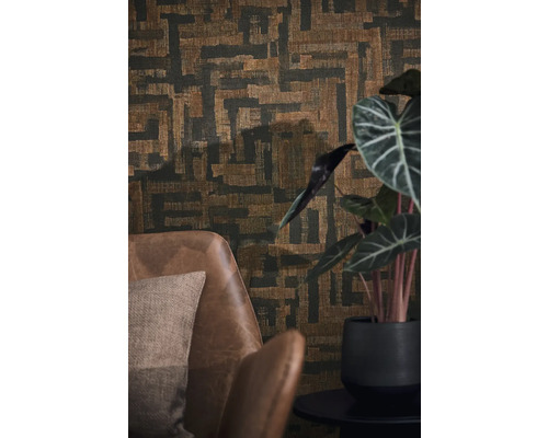 Papier peint intissé avec motif géométrique abstrait et aspect tissé derrière un fauteuil en cuir marron et une plante d'intérieur.