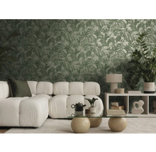 Salon moderne et lumineux avec canapé blanc, table en verre et papier peint intissé à motif de feuilles tropicales vertes.