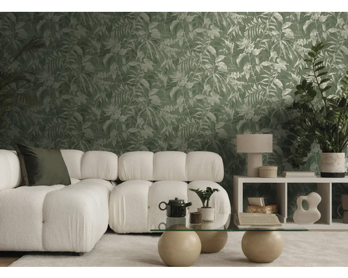 Salon moderne et lumineux avec canapé blanc, table en verre et papier peint intissé à motif de feuilles tropicales vertes.