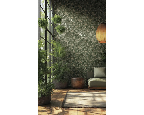 Papier peint intissé avec motif de feuilles tropicales vert et crème dans une pièce lumineuse avec plantes, canapé vert et suspension tressée.