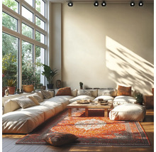 Salon lumineux avec grand canapé modulable, table basse en bois et tapis oriental devant de grandes fenêtres et des spots au plafond.