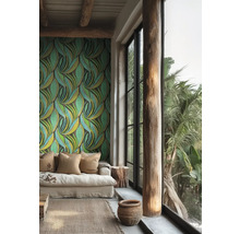 Salon lumineux avec papier peint intissé à motif de feuilles vertes, canapé beige, pilier en bois et grande baie vitrée.