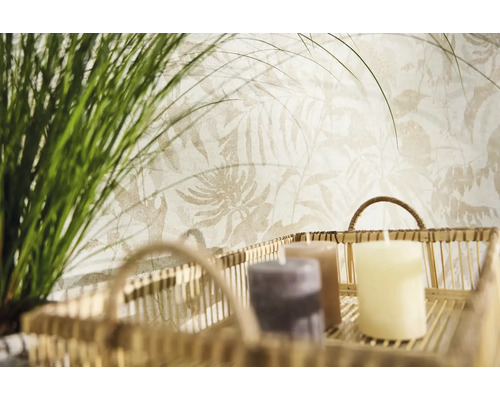 Papier peint intissé avec motif de feuilles botaniques claires derrière un panier décoratif avec bougies et herbes vertes.
