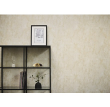 Papier peint intissé aspect béton beige sur un mur derrière une étagère en métal noir avec des objets décoratifs.