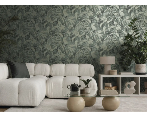 Salon moderne avec papier peint à motif botanique, canapé modulaire blanc et table basse en verre dans une ambiance lumineuse et organisée.