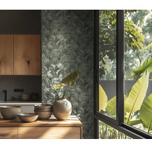 Papier peint à motif de feuilles dans une cuisine lumineuse avec meubles en bois, bols en céramique et un vase devant une fenêtre vue sur nature.