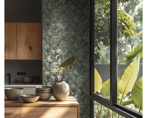 Papier peint à motif de feuilles dans une cuisine lumineuse avec meubles en bois, bols en céramique et un vase devant une fenêtre vue sur nature.
