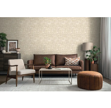 Wohnzimmer mit einer hellen Vliestapete mit geometrischem Muster, braunem Ledersofa, Sessel und Couchtisch.