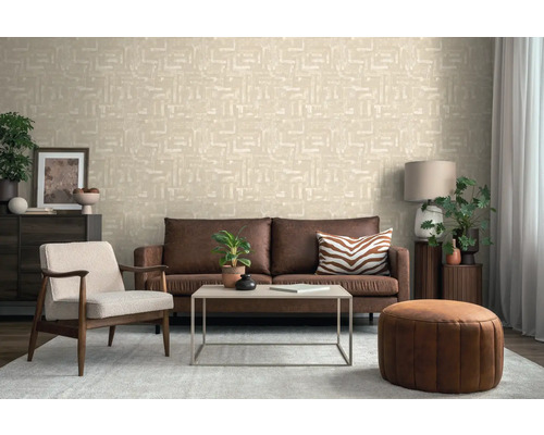 Wohnzimmer mit einer hellen Vliestapete mit geometrischem Muster, braunem Ledersofa, Sessel und Couchtisch.