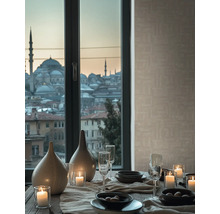 Gedeckter Tisch mit Keramikvasen, brennenden Kerzen und Gläsern vor einem Fenster mit Stadtblick und beige strukturierter Tapete.