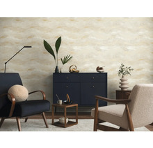 Salon moderne avec papier peint à motif abstrait beige et doré, buffet bleu foncé et deux fauteuils.