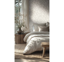 Chambre lumineuse avec papier peint intissé à motif de feuilles, lit en lin et table de chevet en tronc d'arbre.