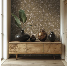 Buffet en bois devant un mur avec du papier peint à motif de feuilles, décoré de divers vases sombres et de grandes feuilles vertes.