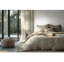Chambre à coucher lumineuse avec papier peint intissé à motif de feuilles, lit avec linge de lit en lin et vue sur le jardin par une baie vitrée.