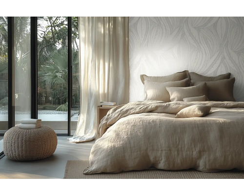 Chambre à coucher lumineuse avec papier peint intissé à motif de feuilles, lit avec linge de lit en lin et vue sur le jardin par une baie vitrée.