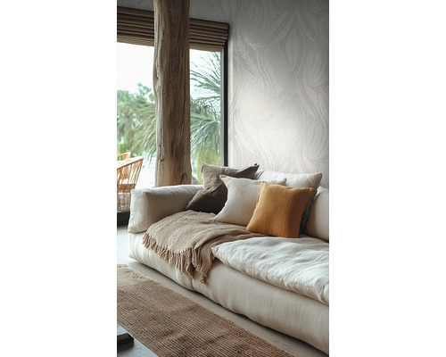 Salon lumineux avec papier peint à motifs botaniques, un canapé en lin avec des coussins et une poutre en bois rustique.
