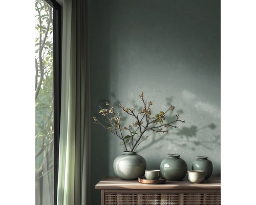 Mur peint en vert avec trois vases en céramique à glaçure craquelée et des branches sur un buffet en bois à côté d'une fenêtre lumineuse.