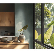 Cuisine moderne avec mur texturé, meubles et plan de travail en bois. Bols en céramique et vase. Grande fenêtre avec vue sur des plantes.