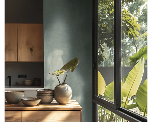 Cuisine moderne avec mur texturé, meubles et plan de travail en bois. Bols en céramique et vase. Grande fenêtre avec vue sur des plantes.