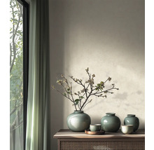 Salon minimaliste avec des vases en céramique émaillée et des branches séchées sur un buffet en bois à côté d une fenêtre.
