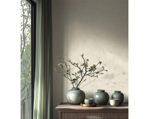 Salon minimaliste avec des vases en céramique émaillée et des branches séchées sur un buffet en bois à côté d une fenêtre.