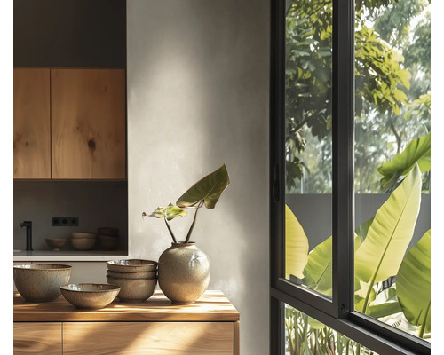Cuisine moderne et lumineuse avec des meubles en bois, des bols en céramique sur un plan de travail en bois et une grande fenêtre sur la verdure.