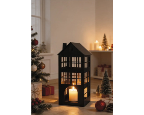 Lanterne noire en métal en forme de maison avec une bougie allumée dans une scène de Noël avec un sapin décoré et des cadeaux.