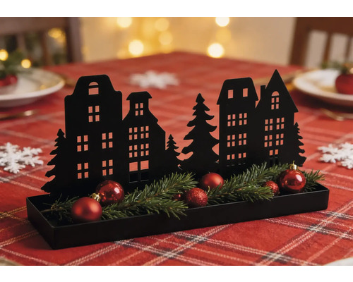 Décoration de Noël noire en métal avec silhouette de maisons, branches de sapin et boules rouges dans un plateau sur une table décorée.