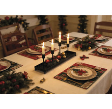 Bougeoir rectangulaire noir en métal avec quatre bougies blanches sur une table de Noël décorée de branches de sapin.
