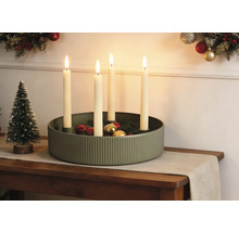 Décoration de Noël festive avec une coupe en métal vert rainuré, quatre bougies allumées, des boules de Noël et un petit sapin décoratif.